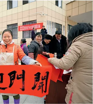  ??  ?? On January 31, 2019, 17,670 residents who had been resettled in the new community converge to celebrate the upcoming New Year in Qiannan Buyi and Miao Autonomous Prefecture of Guizhou Province. A woman displays the Spring Festival couplets she received as a New Year gift.