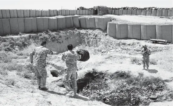  ?? Sebastian Meyer / Corbis via Getty Images ?? Troops dump trash at a burn pit in Zhari, Afghanista­n. The VA argues there’s no proof of long-term health problems linked to the pits.