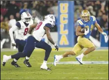  ?? Associated Press ?? UCLA running back Zach Charbonnet (right) avoids Arizona linebacker Sterling Lane II (left) and linebacker Jerry Roberts last Saturday in Pasadena. The Bruins host USC today.