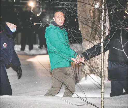  ?? ALEXANDER NEMENOV/AFP VIA GETTY IMAGES ?? Russian opposition leader Alexei Navalny is escorted out of a police station in Khimki, outside Moscow, after a court
ordered him to be jailed for 30 days. Navalny on Monday urged Russians to stage mass anti-government protests.