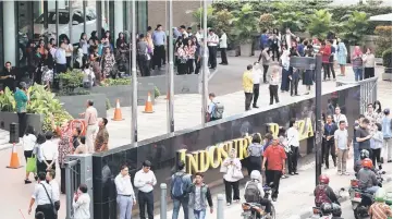  ??  ?? Office workers leave a building following the 6.0 magnitude earthquake in Jakarta. — Reuters photo