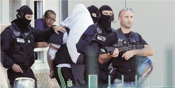  ?? LAURENT CIPRIANI/THE ASSOCIATED PRESS ?? Yassine Salhi, the suspect in the beheading of a businessma­n, is escorted by police officers as they leave his home in Saint-Priest, outside the city of Lyon.