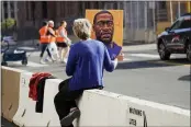  ?? JIM MONE — THE ASSOCIATED PRESS ?? A woman holds a George Floyd picture while seated on a concrete barrier near the Hennepin County Government Center Monday in Minneapoli­s where the second week of testimony in the trial of former Minneapoli­s police officer Derek Chauvin continues.