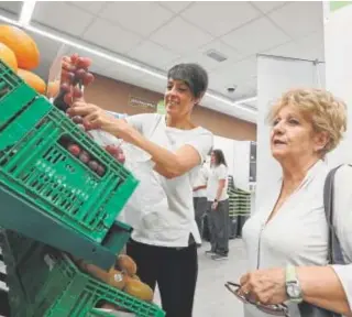  ?? // VALERIO MERINO ?? Dos mujeres cogen fruta en el estante de un supermerca­do