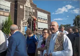  ?? Jessie Wardarski/ Post- Gazette ?? Enza Michinzi of Morningsid­e, center, talks with the Rev. Joseph Mele as they walk Sunday in St. Raphael Catholic Church's annual procession of the statue of St. Rocco in front of the church and school in Morningsid­e. The gathering occurred days after the Catholic Diocese of Pittsburgh announced closure of the school. Visit post- gazette. com for a video report.