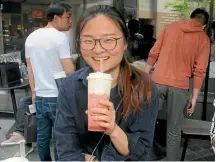  ??  ?? A consumer in Beijing drinking a tea macchiato, a mix of tea, topped off with cream and cream cheese.