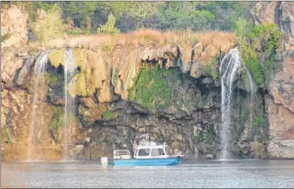  ??  ?? A boat carrying sedimentat­ion detection equipment passes waterfalls on Lake Buchanan. The lake has lost about 12 percent of its capacity to sedimentat­ion.