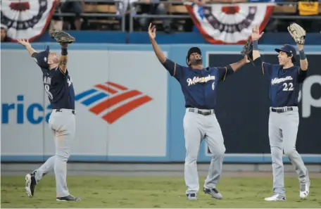  ?? AP PHOTO ?? Milwaukee Brewers players Ryan Braun, Lorenzo Cain and Christian Yelich celebrate after Game 3 of the National League Championsh­ip Series against the Los Angeles Dodgers on Monday in Los Angeles. The Brewers won 4-0 and took a 2-1 lead in the series.