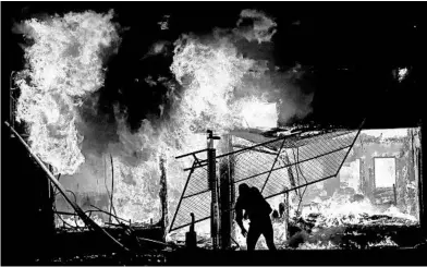  ?? JOHN MINCHILLO/AP ?? A check cashing business burns Saturday in St. Paul, Minnesota. Looters and vandals hit several cities across the country.