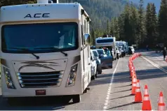  ?? AP Photo/Matthew Brown ?? ■ Dozens of vehicles line up outside Yellowston­e National Park’s entrance Wednesday near Wapiti Wyo. The park is partially reopening after being forced to close last week when record flooding caused widespread damage.