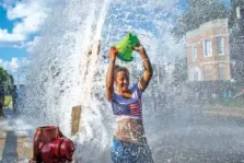  ?? ARMANDO L. SANCHEZ/CHICAGO TRIBUNE/TNS ?? Carol Roby, 28, cools off in an open fire hydrant with friends and neighbors in Chicago’s Englewood neighborho­od last week.