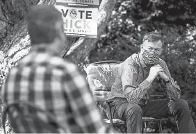  ??  ?? Former Gov. John Hickenloop­er listens to Longmont firefighte­r Micah Holmes during an outdoor roundtable Sept. 19 in Greeley as part of his campaign for U. S. Senate.