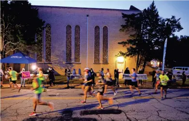  ?? ?? Runners move past the water stop at Voice of Praise Baptist Church in northeast Oklahoma City early in Sunday’s Oklahoma City Memorial Marathon.