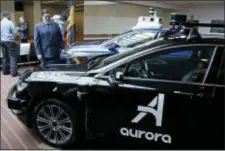  ?? GENE J. PUSKAR — THE ASSOCIATED PRESS ?? Pittsburgh Mayor William Peduto, left, checks out autonomous vehicles designed by Aurora Innovation­s, front, and Argo AI, rear, after signing an executive order outlining objectives and expectatio­ns for the safe testing and developmen­t of autonomous vehicles in Pittsburgh, Monday.