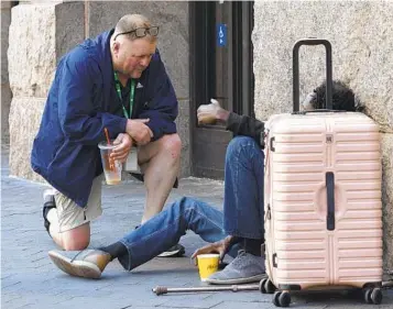  ?? MICHAEL DWYER AP ?? Michael Andrick, director of outreach at the Pine Street Inn, talks with a homeless man in Boston in August.