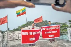  ??  ?? RIGHT
Union leaders Ye Yint (left) and Maung Moe hold protest signs for a photo to post on social media, outside the offices of the Federation of Garment Workers Myanmar in Yangon.