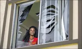  ?? Irfan Khan Los Angeles Times ?? TAMETRA SHAW, 31, looks through a window of her apartment that was shattered in a powerful explosion caused by fireworks stored at a home in Ontario.