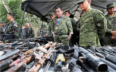  ??  ?? Duterte inspecting firearms during his visit to a military camp in Marawi. — Reuters