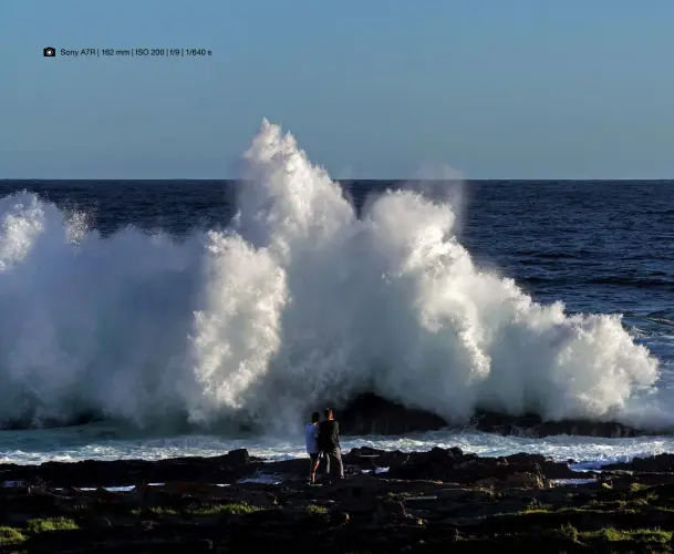  ?? Sony A7R | 162 mm | ISO 200 | f/9 | 1/640 s ?? Menschen als Maßstab Südafrika, Ost-Kap, Storms River Mouth: Die relativ glatte Meeresober­fläche lässt kaum erahnen, dass an den Uferfelsen eine derart dramatisch­e Brandung entsteht. Die Personen im Vordergrun­d liefern den Maßstab, der Horizont ist...