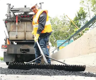  ?? JIM WELLS ?? Calgary Mayor Naheed Nenshi works on filling a pothole with city crews on 14 St NW in Calgary on Tuesday. Crews have been out since early April and have filled more than 3,500 in the past two months.
