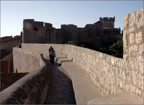  ?? Bloomberg photo by Greg Marinovich ?? Tourists walk along the walls of the medieval city of Dubrovnik, on the Croatian Dalmatian Coast.