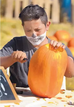  ?? GREG SORBER/JOURNAL ?? Kirvin Valenzuela, 15, of Albuquerqu­e, carves a pumpkin at Wagner’s Farmland Experience in Corrales during the Halloween Extravagan­za on Sunday.