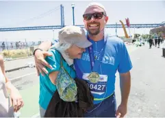  ??  ?? Last-place finisher Brendan Mahoney, who clocked in at six hours for the 26.2-mile race, gets a hug from his mother, Cindy Mahoney.