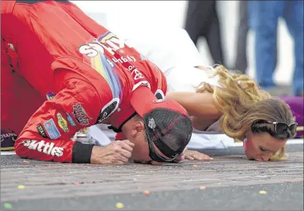  ?? BOBBY ELLIS/GETTY IMAGES ?? Kyle Busch, driver of the No. 18 Toyota, performs the traditiona­l kissing of the bricks with his wife, Samantha, after winning the NASCAR Sprint Cup Combat Wounded Coalition 400 at Indianapol­is Motor Speedway on Sunday. Busch also won Saturday’s...