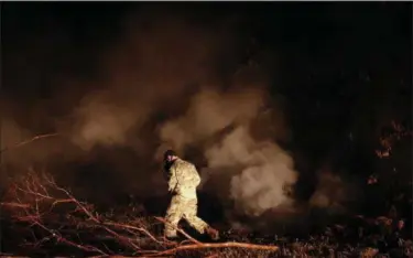  ?? JAE C. HONG — THE ASSOCIATED PRESS ?? Sgt. 1st Class Carl Satterwait­e, of the U.S. National Guard, tests air quality near cracks emitting volcanic gases from a lava flow in the Leilani Estates subdivisio­n near Pahoa, Hawaii Thursday. Kilauea has destroyed more than 35 structures since it...