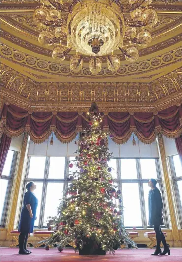  ?? ?? ↑ Members of the Royal Collection Trust with a Christmas tree in the Crimson Drawing Room