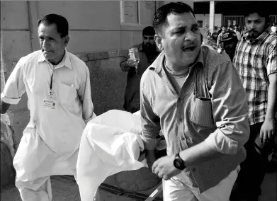  ?? ASIF HASSAN / AGENCE FRANCE-PRESSE ?? Pakistani paramedics push a stretcher carrying an injured Chinese national into a hospital after he was shot in Karachi on Monday.