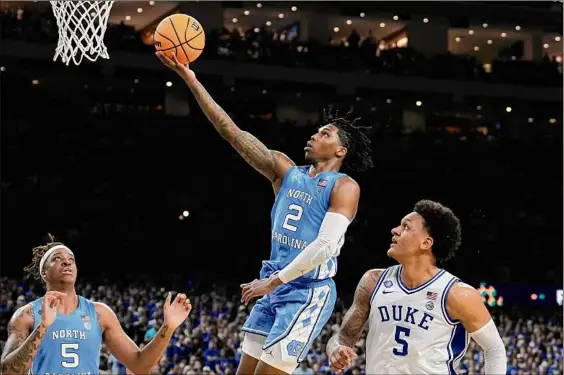  ?? Brynn Anderson / Associated Press ?? North Carolina's Caleb Love scores ahead of Duke's Paolo Banchero, right, during the second half of their game in the semifinal round of the NCAA Tournament on Saturday. Love scored 22 of his 28 points in the second half for the Tar Heels.