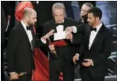  ?? ASSOCIATED PRESS ?? “La La Land” producer Jordan Horowitz, left, presenter Warren Beatty, center, and host Jimmy Kimmel right, look at an envelope announcing “Moonlight” as best picture at the Oscars on Sunday at the Dolby Theatre in Los Angeles. It was originally...