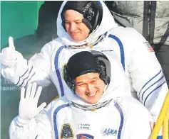  ??  ?? NASA astronaut ScottTingl­e (top) and Norishige Kanai of the Japan Aerospace Exploratio­n Agency wave as they climb a ladder to the rocket at the Russian-leased Baikonur Cosmodrome in Kazakhstan. — AFP photo