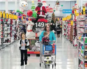  ?? DAVID J. PHILLIP / THE ASSOCIATED PRESS FILES ?? Shoppers walk down an aisle at a Walmart Supercente­r in Houston. “We still feel pretty good about the consumer,” Walmart chief financial officer Brett Biggs says.