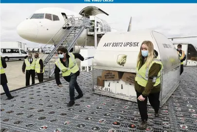  ?? POOL Getty Images ?? UPS employees move one of two containers with the first shipments of the FDA-approved Pfizer COVID-19 vaccine at a ramp at UPS Worldport in Louisville, Kentucky, on Sunday. The flight originated in Lansing, Michigan.