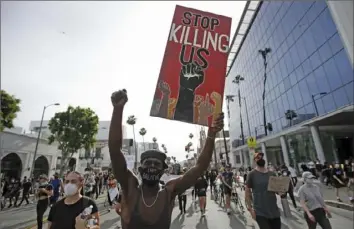  ?? Marcio Jose Sanchez/Associated Press ?? A protester carries a sign in the Hollywood area of Los Angeles on June 1, 2020, during demonstrat­ions after the killing of George Floyd. Floyd’s death sparked calls for a racial reckoning to address issues that have created inequities impacting generation­s of Black Americans.