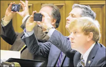  ??  ?? Sens. Jeff Mullis, R-Chickamaug­a, John F. Kennedy, R-Macon (both taking photos with their phones), and Blake Tillery, R-Vidalia, watch the vote board after the recent vote on SB 16. The Senate faces criticism for not allowing streaming as part of...