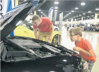  ?? PHOTOS BY CARLINE JEAN/STAFF PHOTOGRAPH­ER ?? Larry Lindberg of Weston and his son Henry, 5, check out the engine on a 2017 Alfa Romeo Giulia.