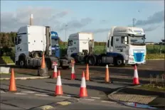  ??  ?? Drivers park their cabs at a truck stop as they wait to pick up trailers arriving from Dublin.