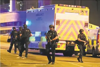  ?? Peter Byrne / Associated Press ?? Armed police work at Manchester Arena after an explosion struck at the end of an Ariana Grande show. Police said the bombing was being treated as a terrorist act.