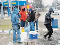  ?? DAVID J. PHILLIP THE ASSOCIATED PRESS ?? Juan Lopez, right, carries a cooler full of water after filling it with a hose from a park spigot Thursday in Houston. Houston and several surroundin­g cities are under a boil water notice as many residents are still without running water in their homes.