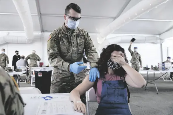  ?? LYNNE SLADKY/AP ?? IN THIS APRIL 5 FILE PHOTO, LEANNE MONTENEGRO, 21, covers her eyes as she doesn’t like the sight of needles, while she receives the Pfizer COVID-19 vaccine at a FEMA vaccinatio­n center at Miami Dade College in Miami.