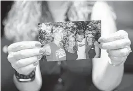  ?? JENNIFER LETT/SOUTH FLORIDA SUN SENTINEL ?? Christie King holds up a photo of her sister Jessica (left), her newly found sister, Sally Griffith (center), her father, Bob (center right) and Christie (right).
