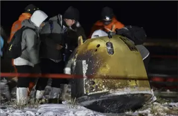  ?? Associated Press ?? Recovery crew members inspect the capsule of the Chang’e 5 probe after it landed Thursday in northern China's Inner Mongolia Autonomous Region. The Chinese lunar capsule returned to Earth with the first fresh samples of rock and debris from the moon in more than 40 years. China joins the U.S. and Russia in successful­ly landing a craft on the moon.