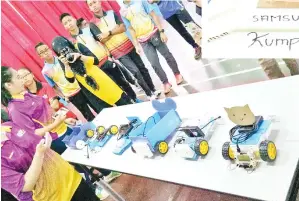  ??  ?? PELAJAR membentang­kan kereta elektrik yang dicipta di depan penilai.