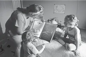  ?? BARBARA J. PERENIC/COLUMBUS DISPATCH ?? Em Hughes reads to her children, Ben, 5, and Seb, 3, on Monday at her home on Columbus’ Far East Side. Hughes is nine weeks pregnant as a first-time surrogate. Her family also includes husband Jeff and German shepherd Oracle.