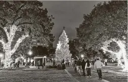  ?? Billy Calzada / Staff photograph­er ?? People arrive at Travis Park to see the city’s official Christmas tree, which is sponsored by H-E-B. When the lights came on, people clapped and cheered.