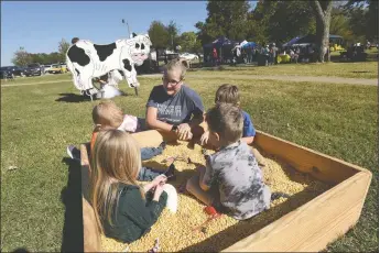  ?? NWA Democrat-Gazette/Flip Putthoff ?? Christine Austin helps youngsters on Saturday play in a sandbox full of corn kernels at the Highfill Fall Festival at Highfill City Park. Airport officials said Highfill has benefited from tax dollars generated by the airport, but the airport gets no services from Highfill in return.