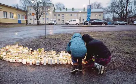  ?? AFP PIC ?? People placing candles and flowers to pay tribute to victims of the shooting in front of the Viertola School in Vantaa, Finland, on Tuesday.